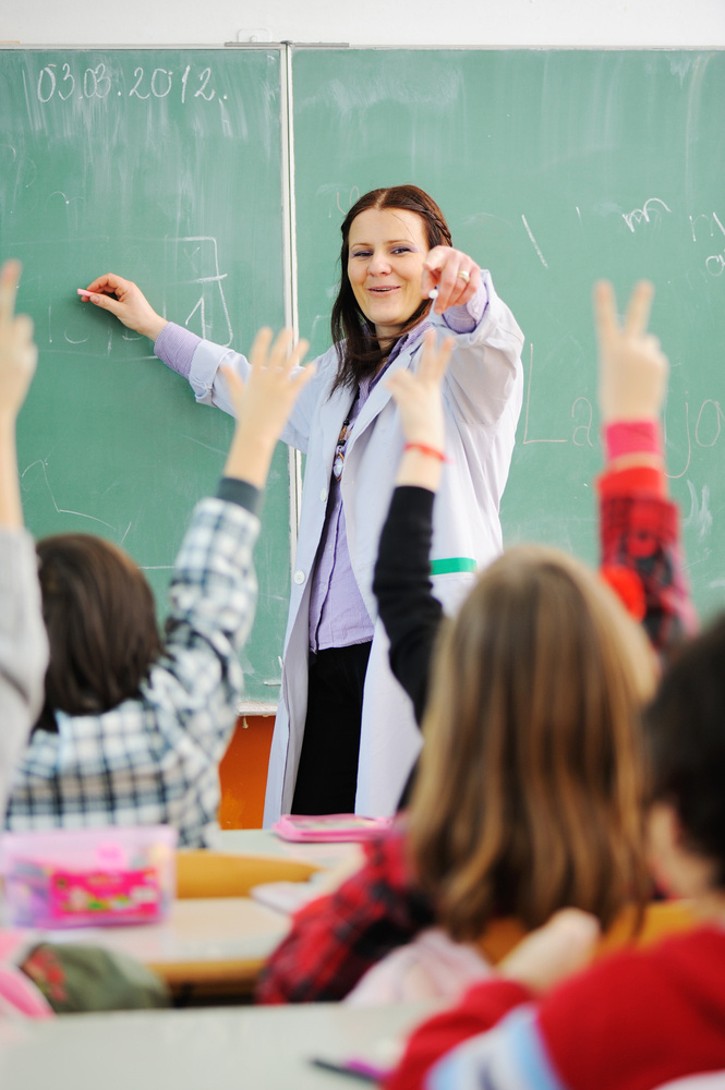 Teacher in classroom and looking at students who raised their arms